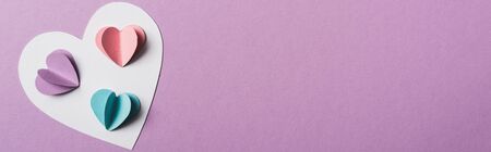 top view of colorful paper hearts on white card on violet background, panoramic shot