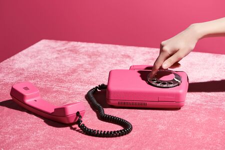 cropped view of woman using retro phone on velour cloth isolated on pink, girlish conceptの写真素材
