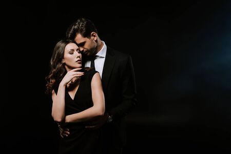sensual man standing with attractive woman in dress on blackの写真素材