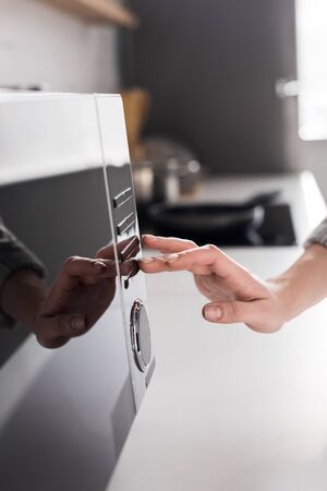 cropped view of woman using microwave in kitchenの写真素材