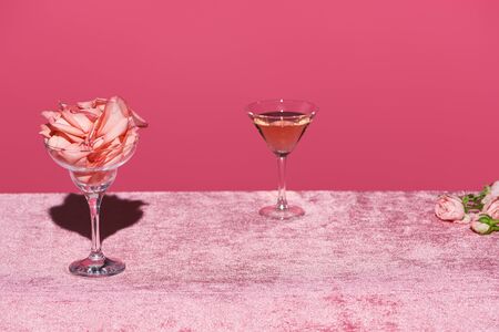rose petals in glass near rose wine on velour pink cloth isolated on pink, girlish conceptの写真素材