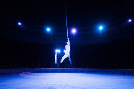 blue light near acrobat performing in arena of circus