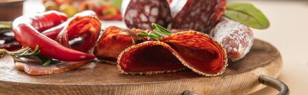 delicious meat platters served with rosemary and chili pepper on wooden board on beige background,...