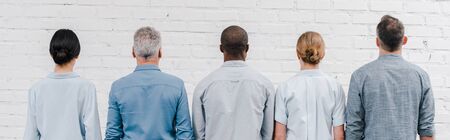 panoramic shot of multicultural people standing near brick wallの写真素材