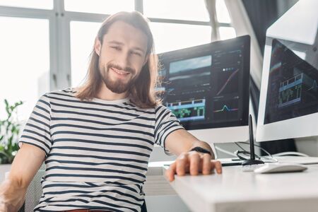 selective focus of happy bearded editor looking at camera