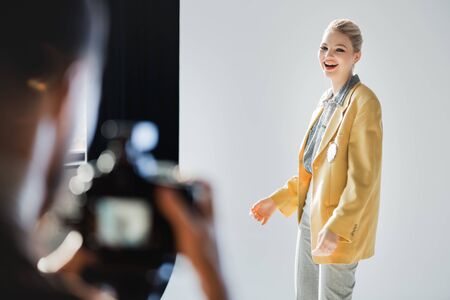 selective focus of smiling and stylish model posing for photographer