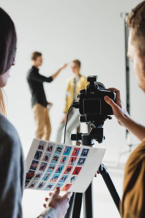 selective focus of producer and photographer holding references and taking photo of model and...