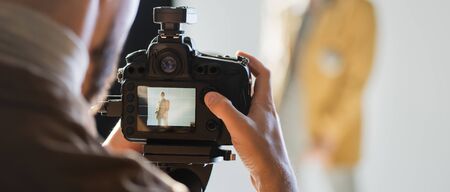 panoramic shot of photographer taking photo of model with digital camera on backstage