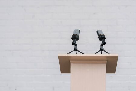 wooden stand with microphones near white brick wall