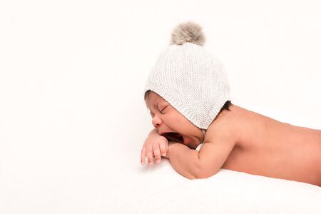 adorable mixed race baby in knitted hat yawning isolated on whiteの写真素材