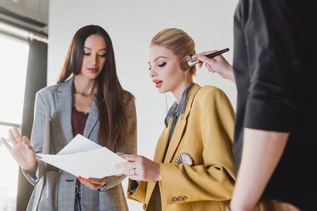 producer talking with model and Makeup Artist doing makeup on backstage