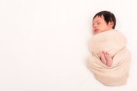 top view of bi-racial baby wrapped in blanket sleeping isolated on whiteの写真素材