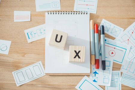 Top view of cubes with ux letters and website ux app development sketches on wooden table