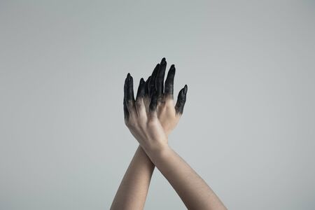 Cropped view of witch hands in black paint isolated on greyの写真素材