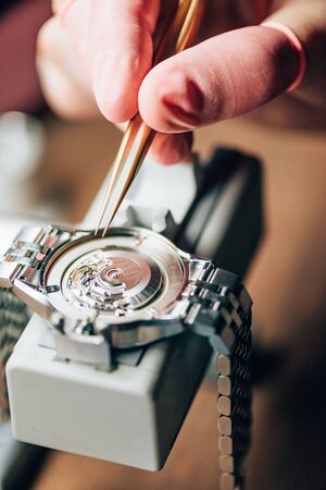 Close up view of watchmaker repairing mechanical wristwatch on movement holderの写真素材