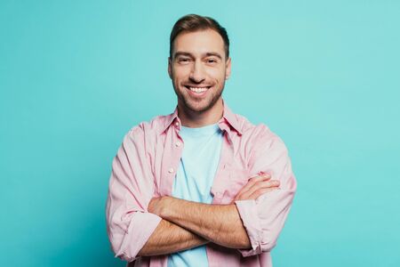 smiling handsome man with crossed arms, isolated on blue