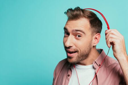 positive bearded man listening music with headphones, isolated on blue