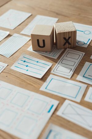 Selective focus of wooden cubes with ux letters by app sketches on table