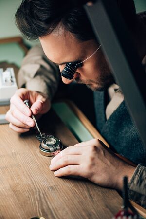 Selective focus of clockmaker working with wristwatch and screwdriver at tableの写真素材