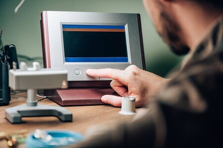 Selective focus of clockmaker working with watch tester at table