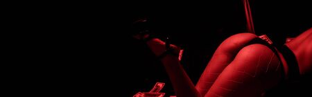 panoramic shot of passionate woman dancing striptease near dollar banknotes isolated on black with...