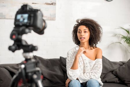 selective focus of young and curly african american girl in braces talking near digital camera