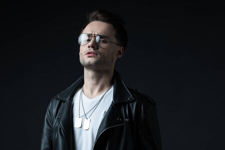 serious stylish brutal man in biker jacket isolated on black