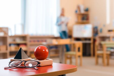 Selective focus of wooden game and eyeglasses with teacher at background in montessori classの写真素材