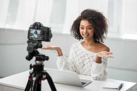 selective focus of cheerful african american video blogger in braces gesturing near digital camera