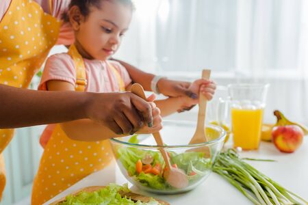 cropped view of african american mother and child mixing fresh saladの写真素材