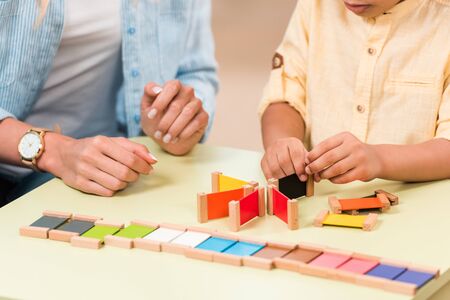Cropped view of kid and teacher playing educational game at table during lesson in montessori classの写真素材