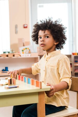 Pensive african american kid playing wooden game in montessori schoolの写真素材