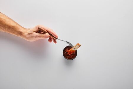 Top view of man putting steak slice in tomato sauce on white backgroundの写真素材