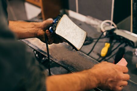 cropped view of worker holding wax iron in repair shopの写真素材
