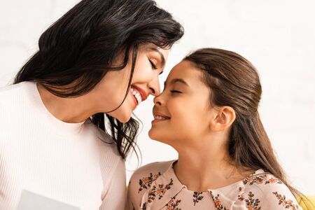happy mom and daughter smiling face to face with closed eyes on mothers dayの写真素材
