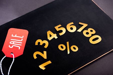 golden numbers with percent sign and red price tag with sale lettering on black backgroundの写真素材