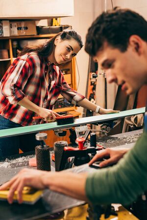 selective focus of smiling worker cleaning ski and looking at colleague in repair shopの写真素材