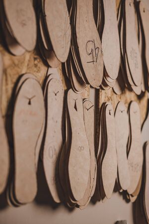 selective focus of footwear insoles of different sizes hanging on wall in workshopの写真素材