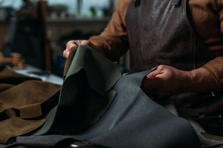 partial view of shoemaker holding piece of genuine leather in workshopの写真素材
