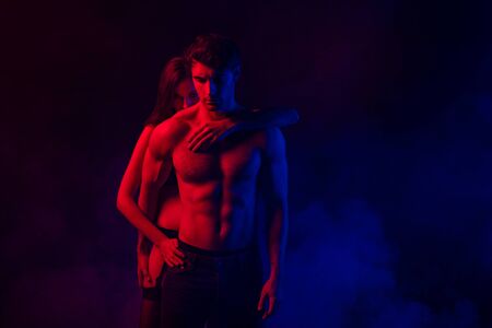 passionate undressed sexy young couple embracing in red and blue light on black backgroundの写真素材