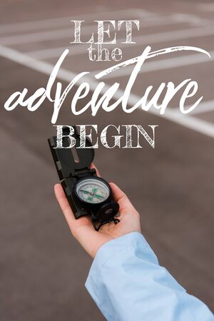 cropped view of woman holding compass near let the adventure begin lettersの写真素材