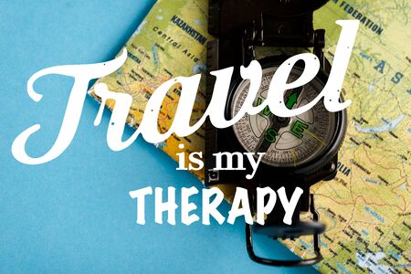 top view of black compass on map near travel is my therapy letters on blue