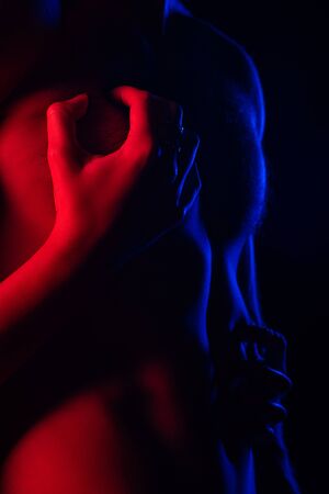 cropped view of passionate man touching sexy boyfriend bare torso in red light isolated on blackの写真素材