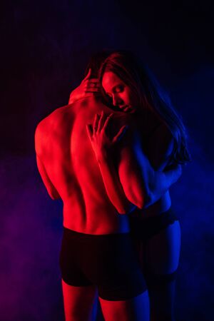 passionate undressed sexy young couple hugging in red lightの写真素材