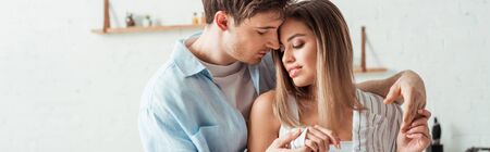 panoramic shot of handsome man touching attractive girl at home