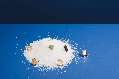 Jewellery rings with gemstones on salt on classic blue background