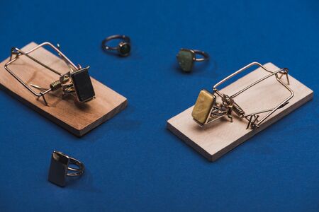 Close up view of mousetraps and jewellery rings on blue surface