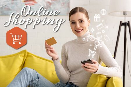 Smiling woman looking at camera while holding smartphone and credit near illustration, online shopping conceptの写真素材