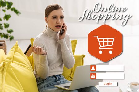 Attractive woman with credit card and laptop talking on smartphone, online shopping conceptの写真素材