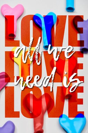 Top view of colorful balloons in heart shape on grey background with all we need is love...